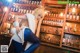 A woman sitting on a stool in front of a bar.