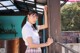 A woman in a school uniform leaning against a wooden door.