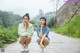 Two young women sitting on the side of a road.