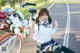 A woman sitting on the ground next to a bike with flowers in it.