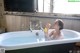 A woman sitting in a bathtub blowing bubbles.