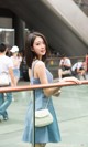 A woman in a blue dress standing next to a railing.