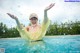 A woman in a yellow dress and a baseball cap in a swimming pool.