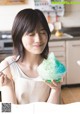 A woman holding a bowl of ice cream in a kitchen.