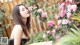 a woman in a black dress standing next to a bush of pink roses