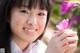 A young woman holding a pink flower in her hand.