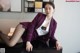 A woman in a purple suit sitting on a black table.