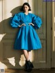 A woman in a blue dress standing in front of a door.